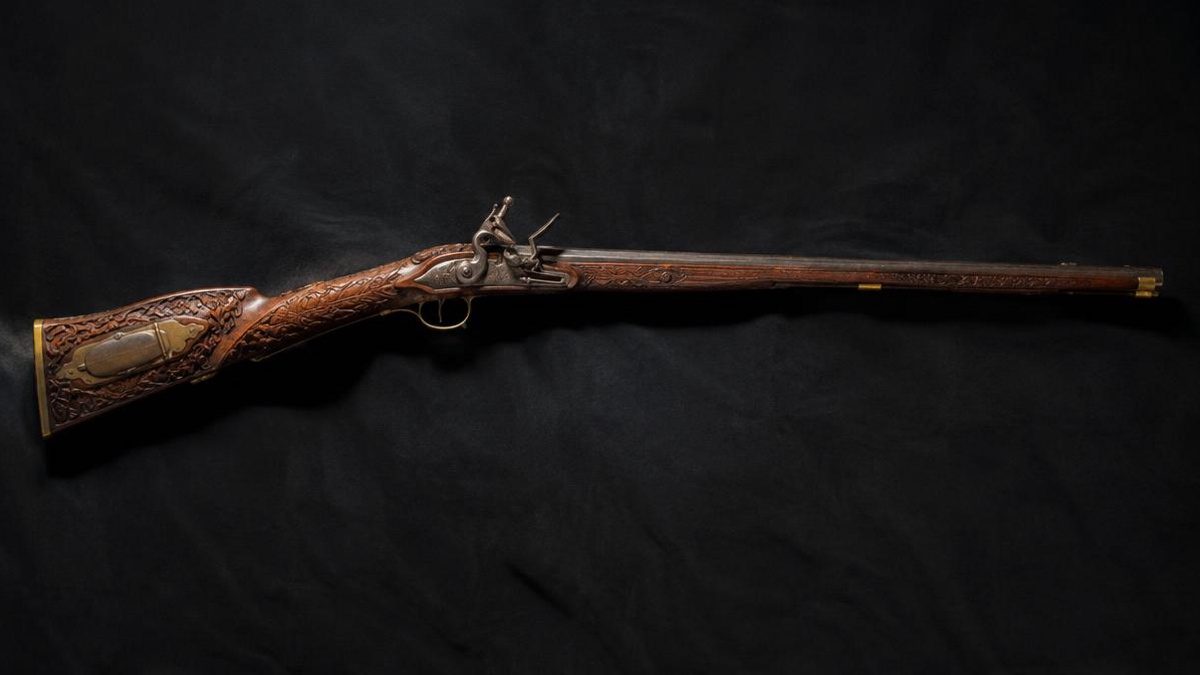 Early flintlock long rifle with carved maple stock against a dark cloth background