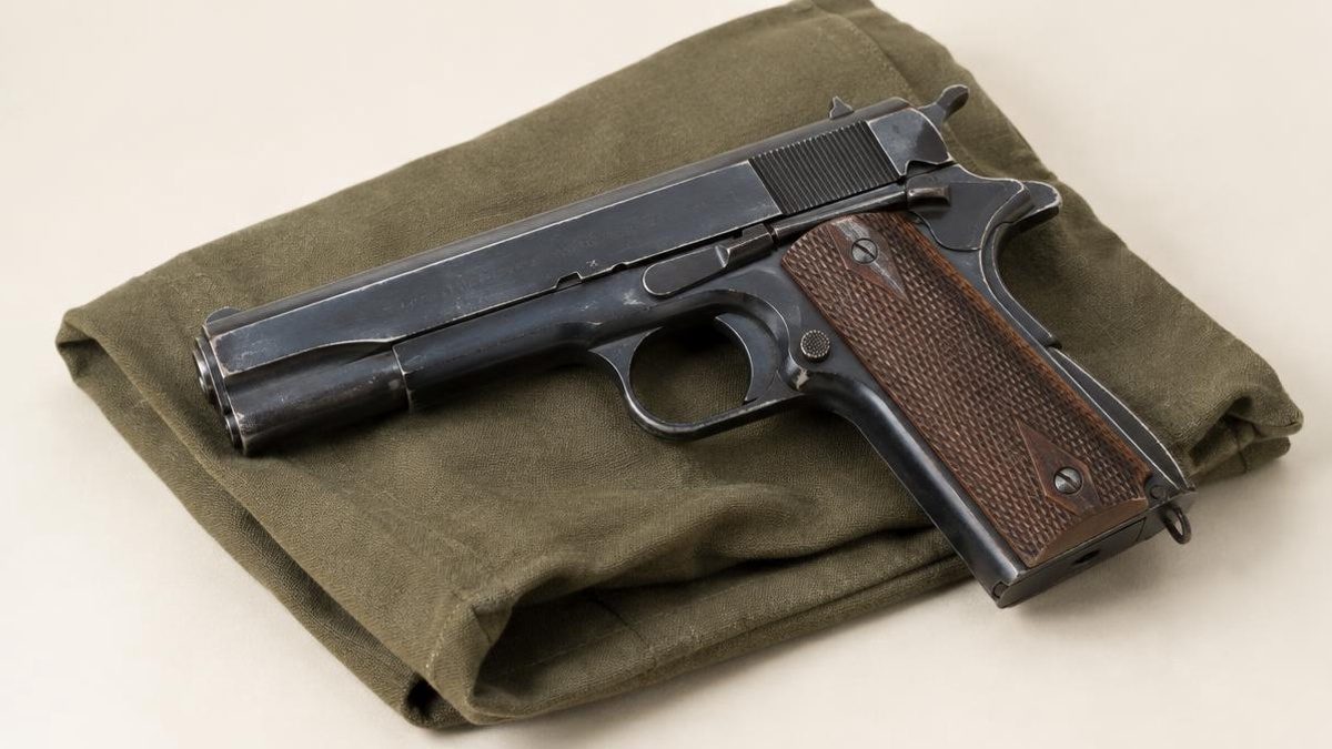 Historic blued service pistol with checkered wooden grips on canvas